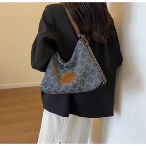 Close-up of blue jacquard canvas tote with brown leather trim and leather chain strap