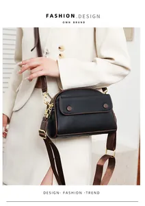 Detail of black pebbled leather shell bag with gold hardware and dual detachable straps