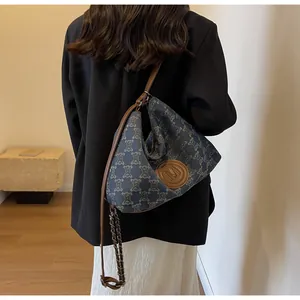 Detail of blue monogram canvas hobo bag with brown leather M logo and chain strap