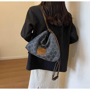 Detail of blue denim hobo bag with vintage pattern and metal chain shoulder strap
