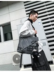 Detail of grey nylon messenger bag with white claw print and plush monkey keychain