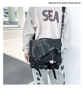 Detail of black nylon messenger bag with white claw graphics and monkey charm