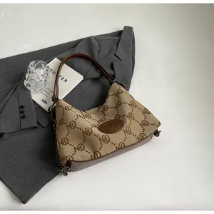 Detailed close-up of khaki canvas tote with M-pattern jacquard and brown leather trim
