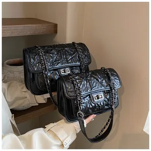 Détail du sac à bandoulière matelassé noir avec chaîne et fermoir pivotant argenté