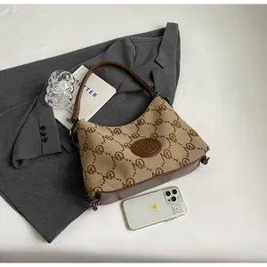 Detail of canvas tote with monogram pattern and leather M logo in a lifestyle setting