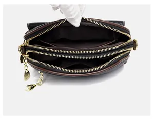 Close-up of a black lychee texture leather shell bag showing three zipper compartments