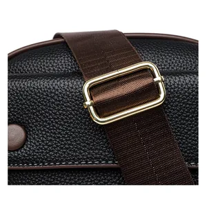 Macro detail of black pebbled leather texture with brown woven strap and gold buckle