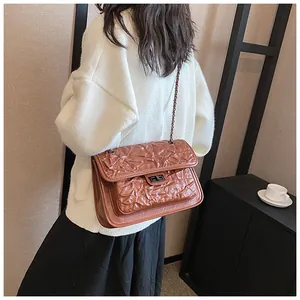 Détail d'un sac à bandoulière matelassé marron avec chaîne et fermoir en métal