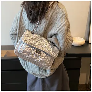 Détail du sac argenté matelassé avec texture plissée métallique et fermoir carré chic