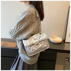 Détail du sac bandoulière argenté matelassé avec chaîne et fermoir pivotant sur modèle
