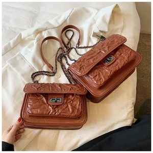 Détail de sacs matelassés marrons avec bandoulières chaîne et fermoir sur un blazer