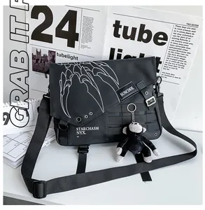 Close-up of black tactical nylon messenger bag with white graphics and a monkey plush charm