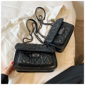 Détail du sac matelassé noir avec chaîne en métal foncé et texture plissée élégante