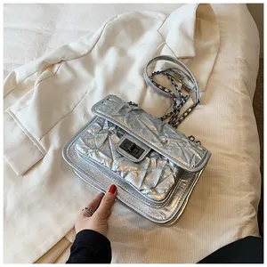 Détail du sac argenté métallisé avec bandoulière chaîne et fermoir rotatif carré