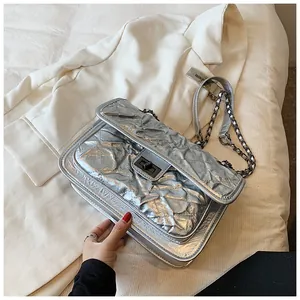 Détail du sac bandoulière argenté matelassé avec chaîne métallique et fermoir rotatif