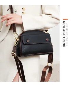 Close-up of black litchi grain leather crossbody bag with brown trim and gold hardware