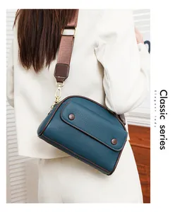 Classic teal leather crossbody shell bag with pebble texture and brown nylon strap