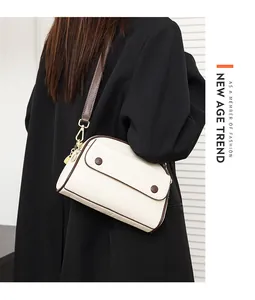 Chic beige crossbody shell bag with brown trim and gold hardware on a black coat