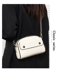 Side view of cream-colored lychee leather shell bag with brown edges and golden zippers