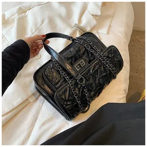 Gros plan sur le sac bandoulière noir matelassé avec fermoir rotatif et chaîne chic