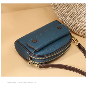 Detail view of deep teal pebbled leather texture and dual zipper design on a shell bag