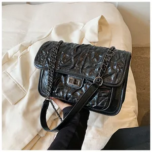 Détail du fermoir rotatif argenté et de la texture matelassée du sac noir
