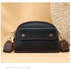 Front detail of black and brown leather crossbody bag with dual-tone finish and gold hardware