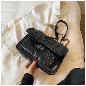 Détail du sac bandoulière noir matelassé avec fermoir rotatif en métal et bandoulière chaîne