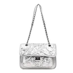 Sac bandoulière argenté matelassé avec chaîne métallique et fermoir sur fond blanc
