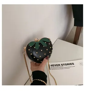Detail of strawberry heart chain bag with black PU leather, gold rivets and green leaf accent