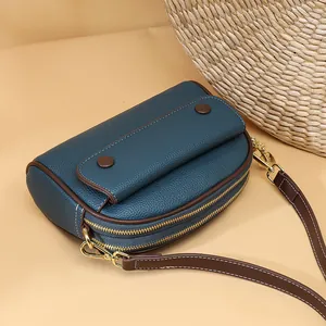 Fashionable dark teal leather shell bag with double zippers and brown shoulder strap