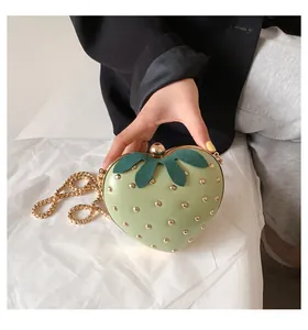 Close-up of light green strawberry bag with gold rivets and metallic chain strap