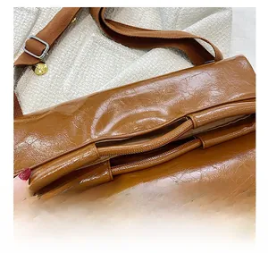Detailansicht des Griffdesigns und der glänzenden Ölwachs-Ledertextur der braunen Tasche