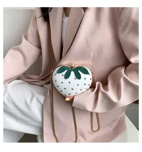 Detail of white strawberry-shaped heart clutch bag with gold studs and chain strap