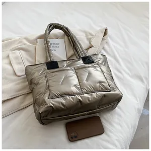 Detail of metallic quilted tote bag with large pockets on stylish neutral bedding background