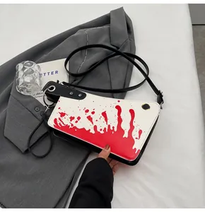 Detailed view of meat cleaver shaped crossbody bag with red blood splatter and black strap