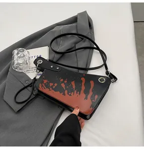 Detail view of black crossbody bag with red splatter pattern and silver metal eyelets