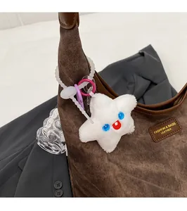 Close-up of a white star-shaped plush keychain accessory hanging on a brown corduroy tote bag