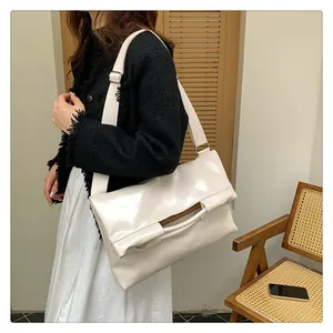 Detail einer weißen glänzenden Ölwachs-Ledertasche mit breitem Gurt im minimalistischen Stil