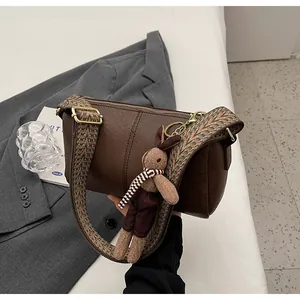 Detail of dark brown leather pillow bag with colorful woven strap and cute bunny charm