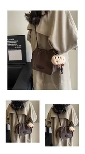 Detail of dark brown suede crossbody bag with drawstring closure and plush pendant