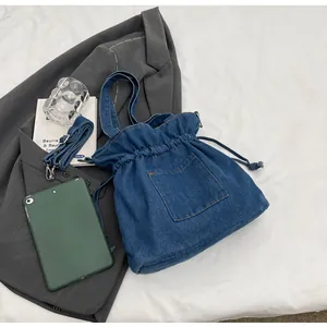 Detail view of denim bucket bag showing drawstring closure and adjustable metal buckle strap