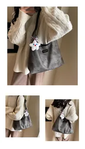 Detail of vintage grey leather tote bag featuring a star plush charm and slim black straps