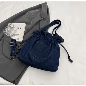 Detail of deep blue denim bucket bag with drawstring closure and silver metal hardware