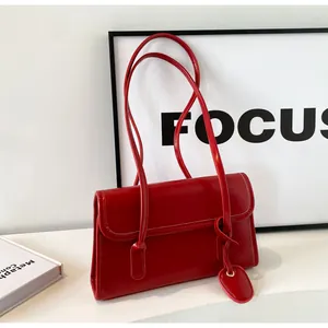 Close-up of a red minimalist leather shoulder bag with a heart-shaped pendant charm
