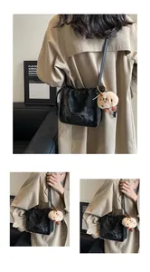 Detail of black pleated cloud bag with soft glossy texture and a cute plush lamb charm