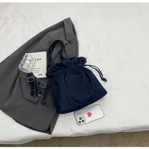 Detailed top view of a dark blue denim drawstring bucket bag with adjustable strap