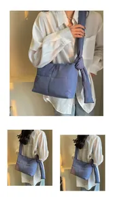 Detail of navy blue quilted puffer bag featuring a large decorative knot on the shoulder strap