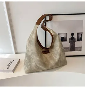 Detail shot of vintage grey tote bag with brown straps and brand label on a minimalist background