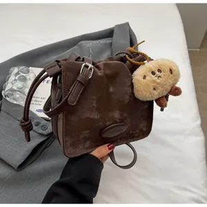 Detailed close-up of retro brown crossbody bag with silver buckle and plush charm